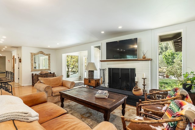 living room with recessed lighting, a brick fireplace, baseboards, and wood finished floors