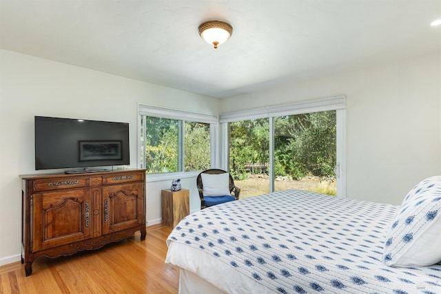 bedroom featuring access to exterior, light wood finished floors, and baseboards