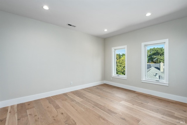 empty room featuring light wood-type flooring, baseboards, visible vents, and recessed lighting