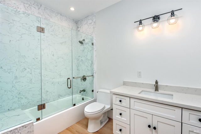 full bathroom with vanity, bath / shower combo with glass door, wood-type flooring, and toilet