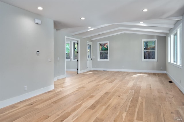 empty room featuring lofted ceiling with beams and light wood-type flooring