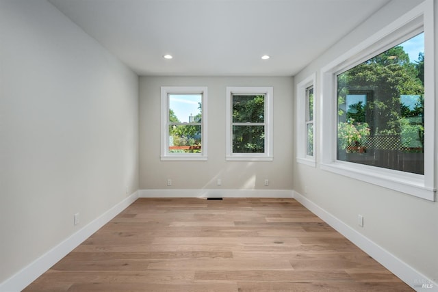 empty room with light wood-type flooring, baseboards, and recessed lighting