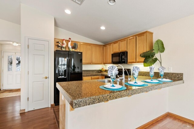 dining space with vaulted ceiling, hardwood / wood-style flooring, and ceiling fan with notable chandelier