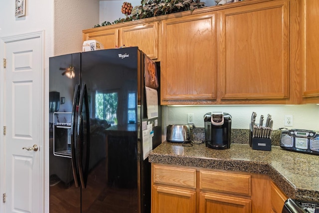 kitchen featuring stainless steel stove and black fridge with ice dispenser