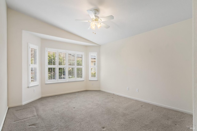 empty room featuring vaulted ceiling, carpet floors, a ceiling fan, and baseboards