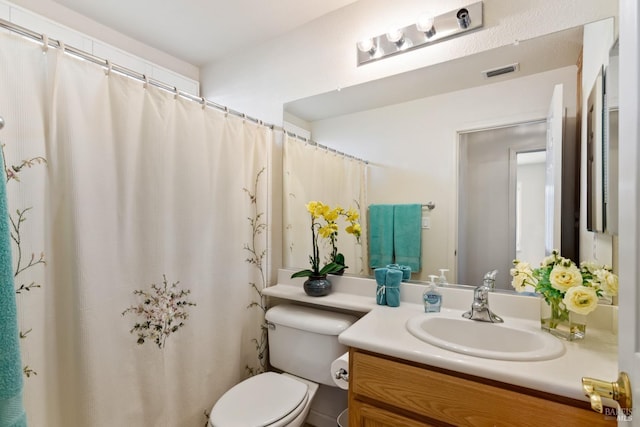 full bathroom featuring toilet, vanity, and visible vents