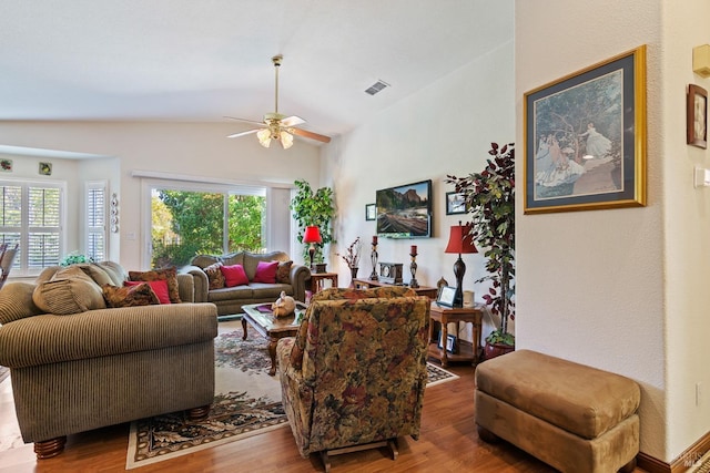 living room with lofted ceiling, visible vents, ceiling fan, and wood finished floors