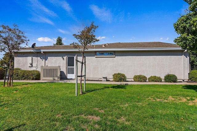 back of house featuring a yard and stucco siding