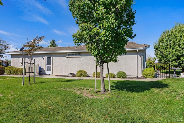 back of property with stucco siding, fence, a patio, and a yard