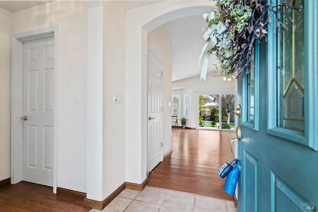 foyer entrance featuring arched walkways, baseboards, and light tile patterned floors