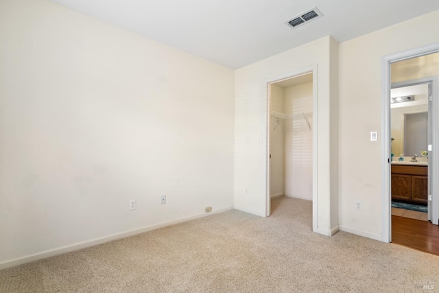 unfurnished bedroom with light carpet, baseboards, a spacious closet, and visible vents