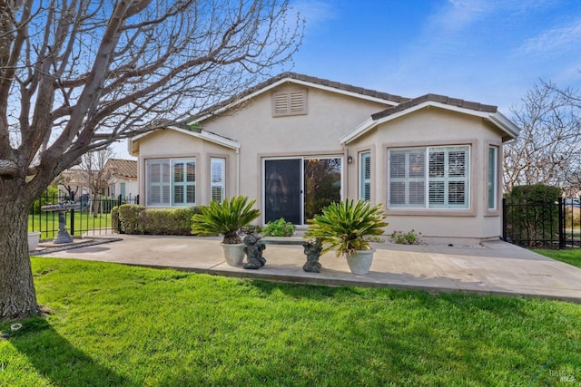 rear view of house with a patio, fence, a lawn, and stucco siding