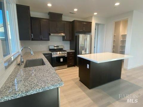 kitchen with decorative backsplash, sink, stainless steel appliances, and light hardwood / wood-style flooring