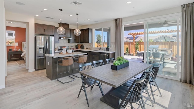 kitchen featuring appliances with stainless steel finishes, tasteful backsplash, sink, light hardwood / wood-style flooring, and a center island