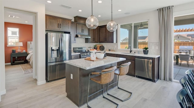 kitchen with a center island, sink, decorative backsplash, light hardwood / wood-style floors, and stainless steel appliances