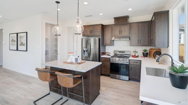 kitchen featuring a center island, sink, decorative light fixtures, light hardwood / wood-style floors, and stainless steel appliances