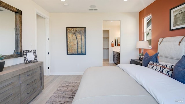 bedroom with connected bathroom and light hardwood / wood-style flooring