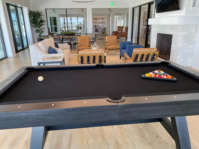 rec room with wood-type flooring, a stone fireplace, and billiards