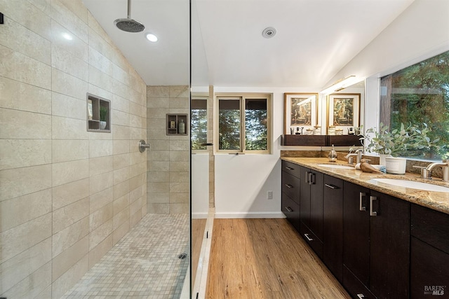 bathroom with tile walls, vaulted ceiling, vanity, wood-type flooring, and a tile shower