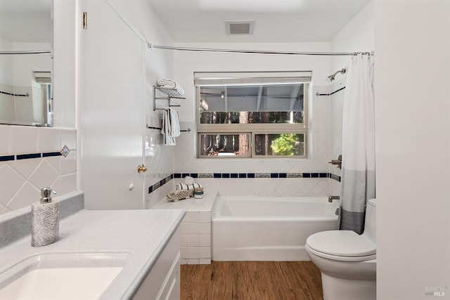 full bathroom with tile walls, shower / bathtub combination with curtain, vanity, hardwood / wood-style flooring, and toilet