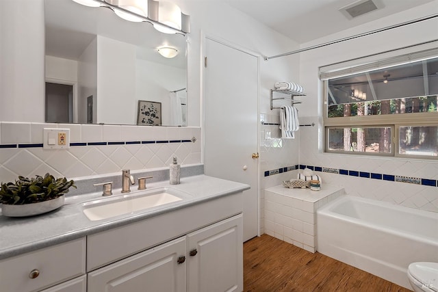 full bathroom featuring vanity, backsplash, hardwood / wood-style flooring, plus walk in shower, and toilet