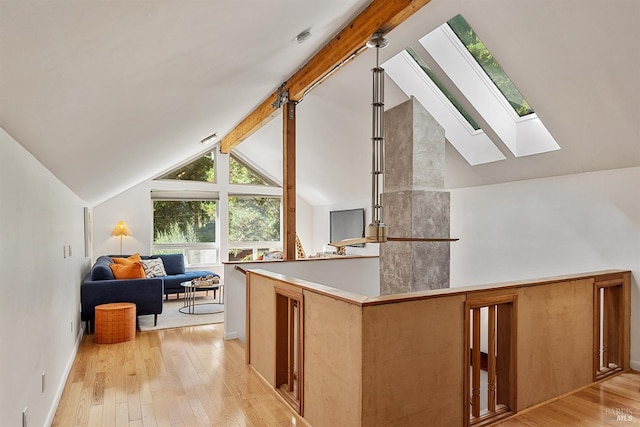 kitchen with light wood-type flooring, hanging light fixtures, and lofted ceiling with skylight