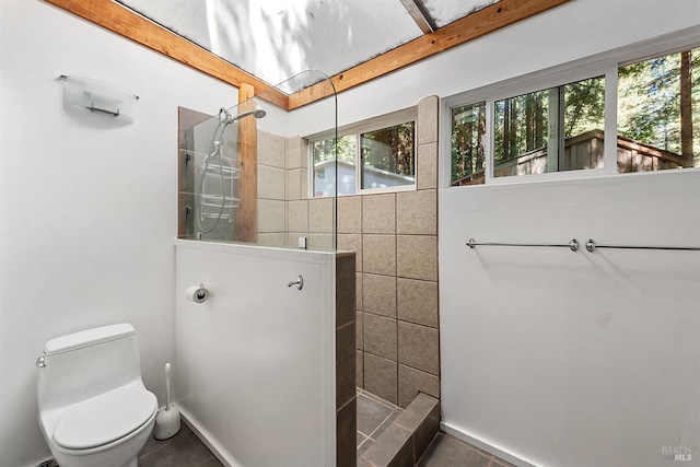 bathroom featuring tiled shower, toilet, and tile patterned flooring