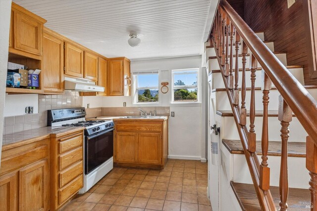 kitchen with tasteful backsplash, sink, tile countertops, light tile patterned floors, and white range with gas cooktop