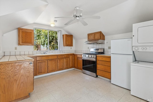 kitchen featuring stacked washer and dryer, white refrigerator, lofted ceiling, ceiling fan, and stainless steel range