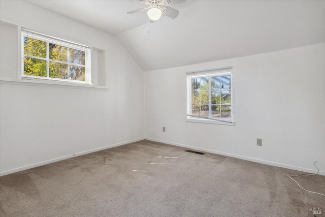 empty room with vaulted ceiling, ceiling fan, and carpet floors