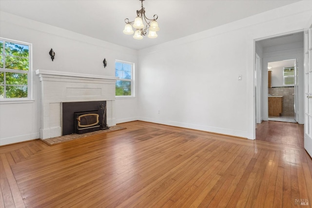 unfurnished living room with a notable chandelier, a fireplace, and hardwood / wood-style floors