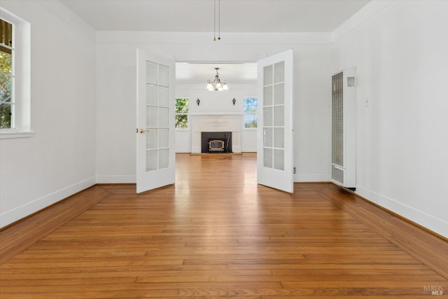 spare room featuring light wood-type flooring, ornamental molding, an inviting chandelier, and french doors