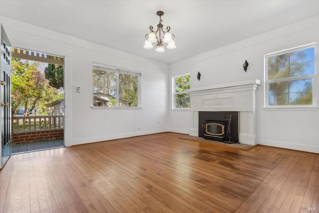 unfurnished living room featuring wood-type flooring, an inviting chandelier, and a fireplace