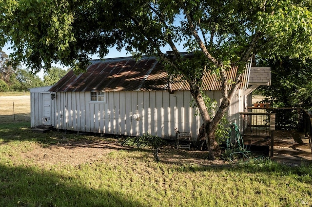 view of property exterior featuring a lawn, an outdoor structure, and a wooden deck