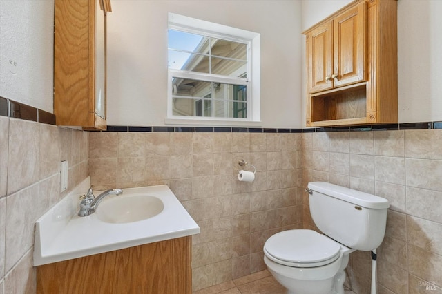 bathroom featuring vanity, tile walls, and toilet