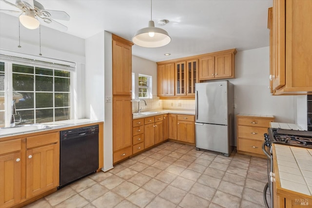 kitchen featuring tile counters, sink, stainless steel appliances, backsplash, and ceiling fan