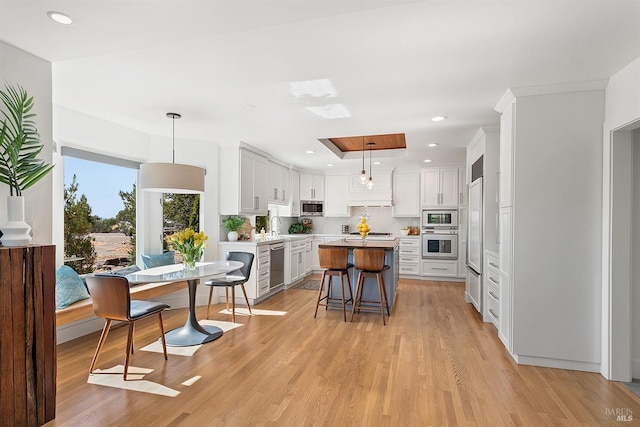 kitchen with a breakfast bar area, a center island, pendant lighting, stainless steel appliances, and white cabinets