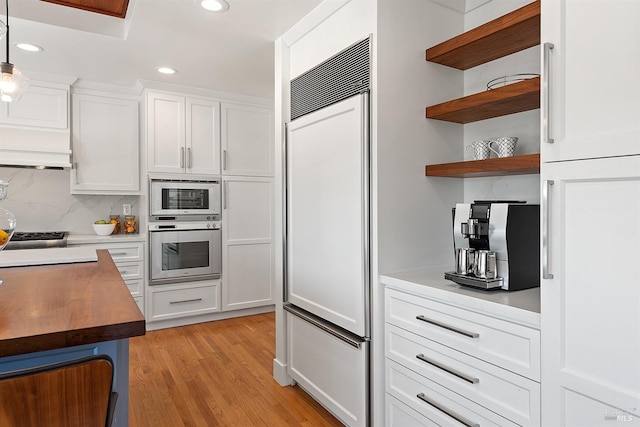 kitchen with white cabinetry, pendant lighting, oven, and paneled built in refrigerator