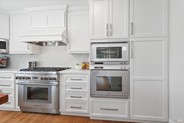 kitchen with appliances with stainless steel finishes, light hardwood / wood-style floors, and white cabinets