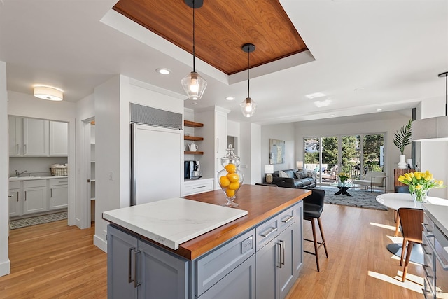 kitchen featuring gray cabinetry, a tray ceiling, decorative light fixtures, and a center island