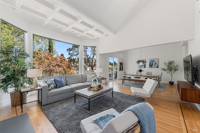 living room featuring a towering ceiling, coffered ceiling, beam ceiling, and light hardwood / wood-style flooring