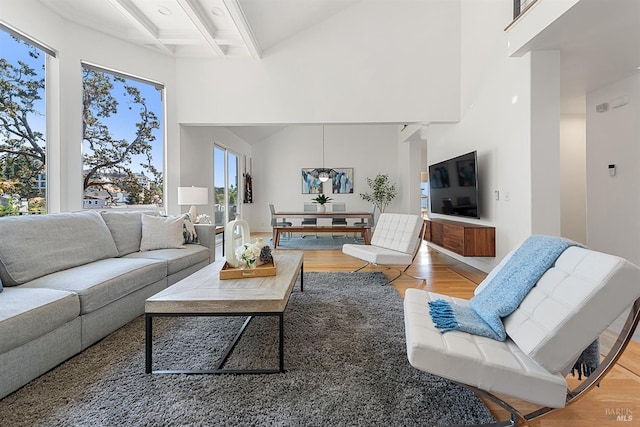 living room with hardwood / wood-style flooring, a towering ceiling, coffered ceiling, and beamed ceiling