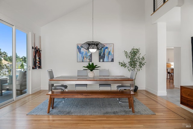 dining room with wood-type flooring and high vaulted ceiling