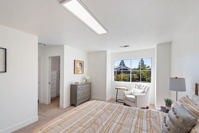 bedroom featuring a walk in closet and light carpet