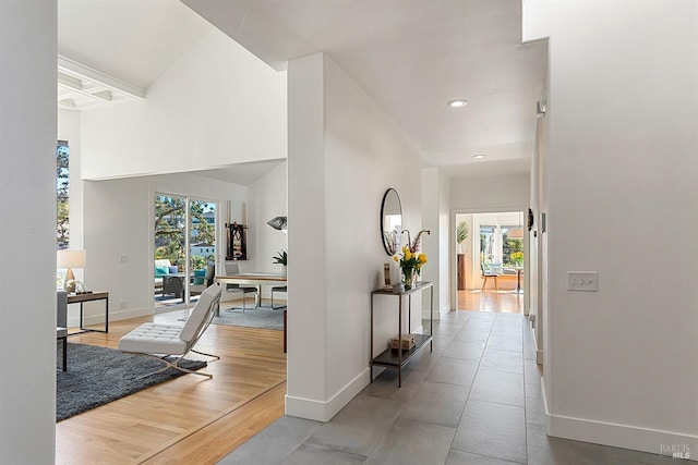 corridor featuring coffered ceiling, plenty of natural light, beamed ceiling, and light wood-type flooring