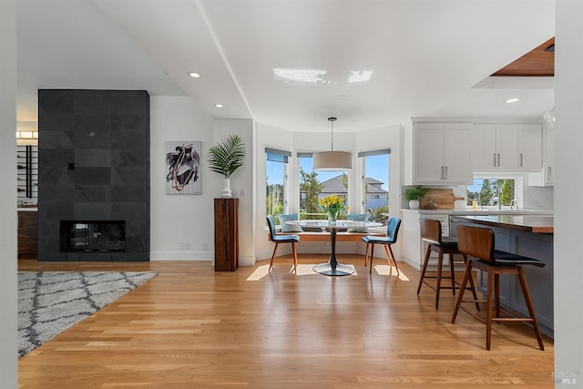 dining room featuring a tiled fireplace and light hardwood / wood-style flooring