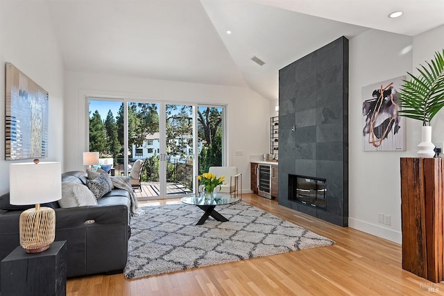 living room featuring lofted ceiling, beverage cooler, and light wood-type flooring