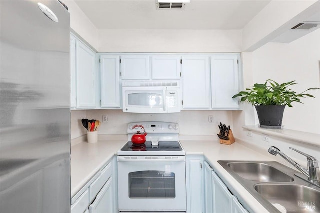 kitchen with white appliances, white cabinetry, and sink