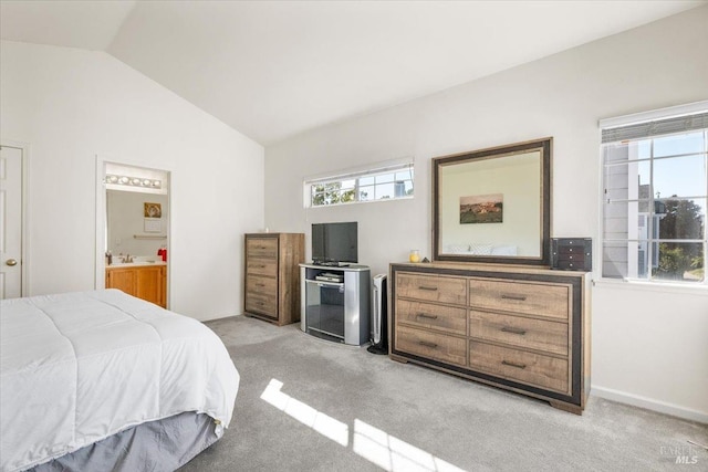 carpeted bedroom with ensuite bath and vaulted ceiling