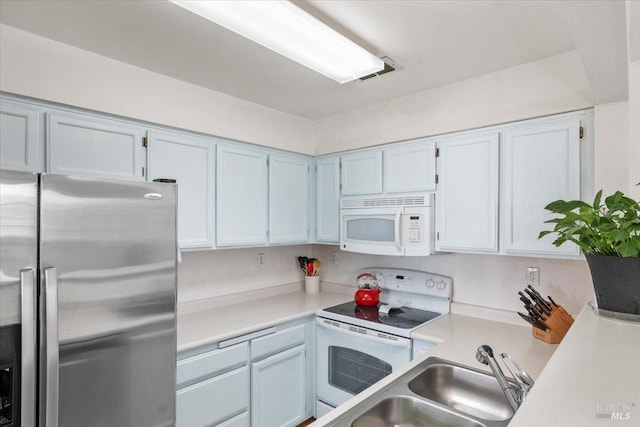 kitchen with white cabinets, sink, and white appliances